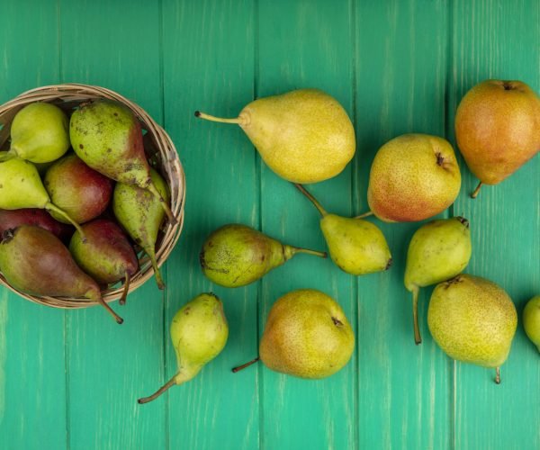 top view of peaches in basket and on green background